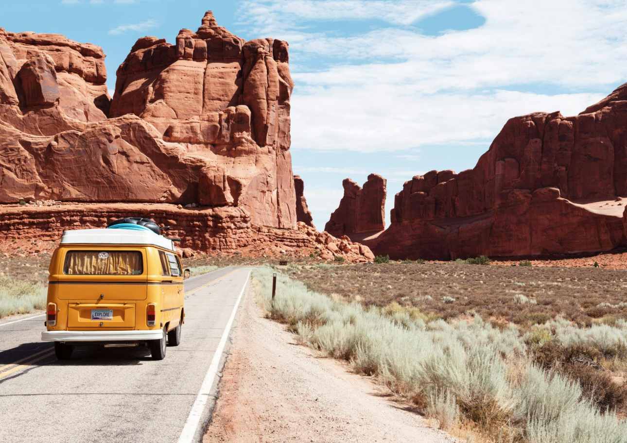 Yellow van driving through desert canyon landscape