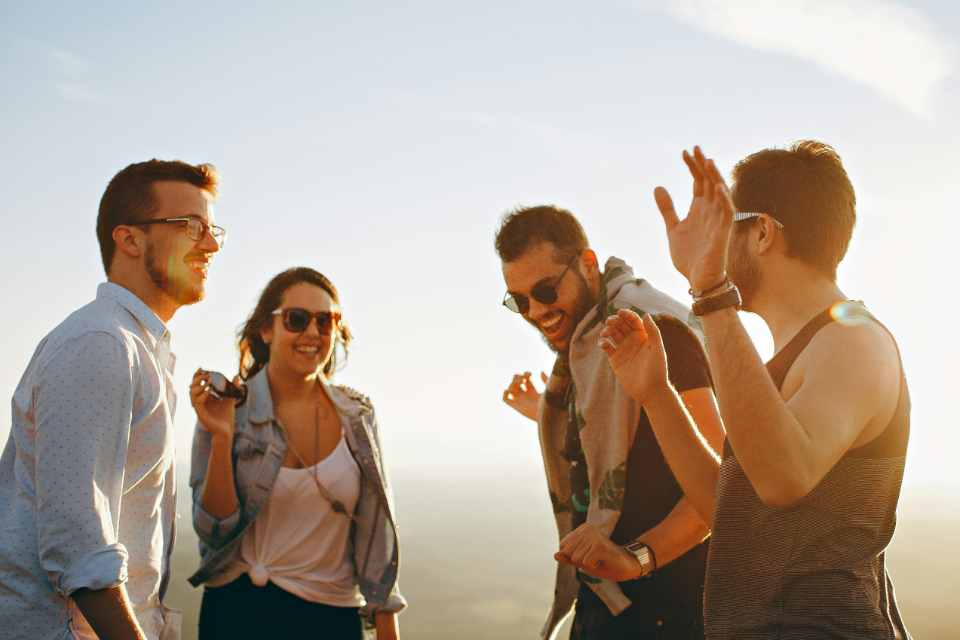 Group of friends laughing and enjoying sunset.