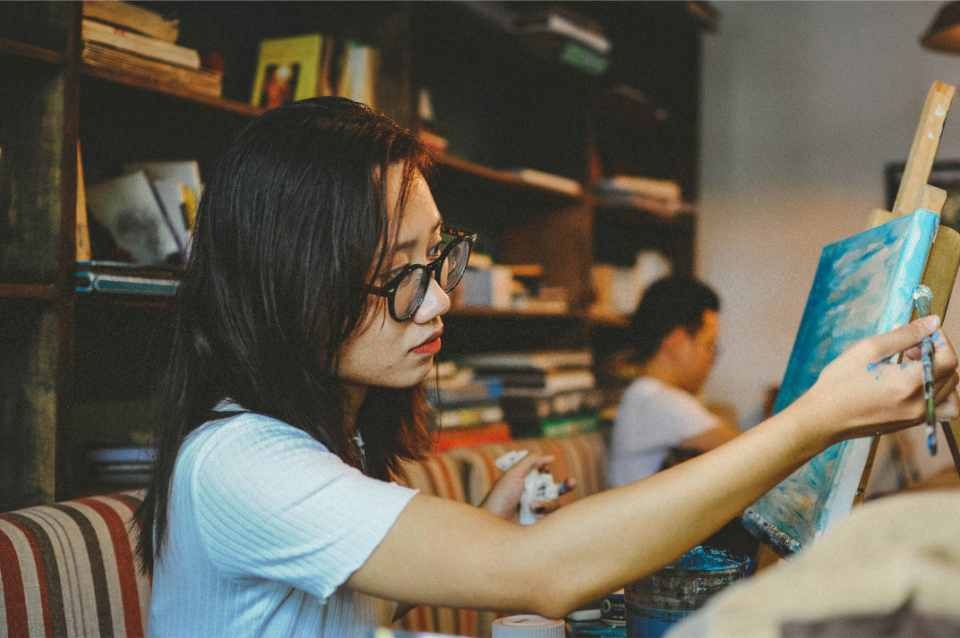 Woman concentrating on painting canvas artwork.