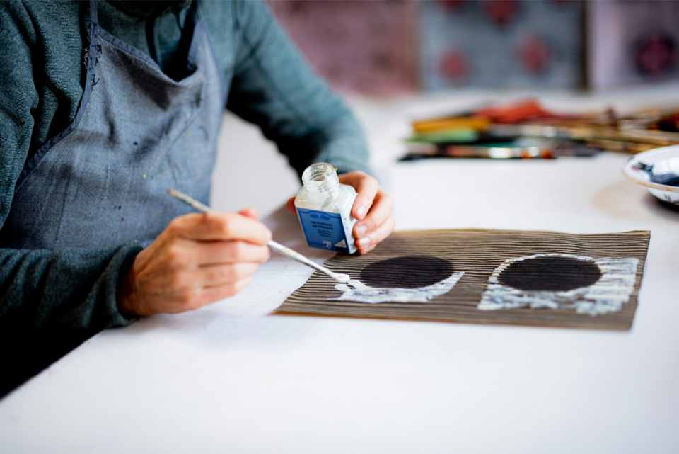 Artist painting geometric designs using white paint.