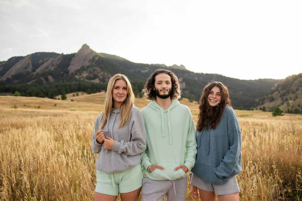 Three friends posing outdoors in casual hoodies.